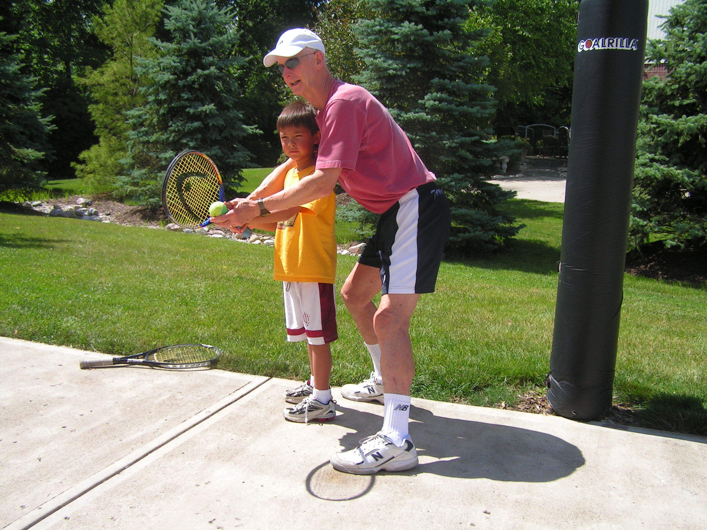 Ed Brune teaching a young player how to hold a tennis racquet